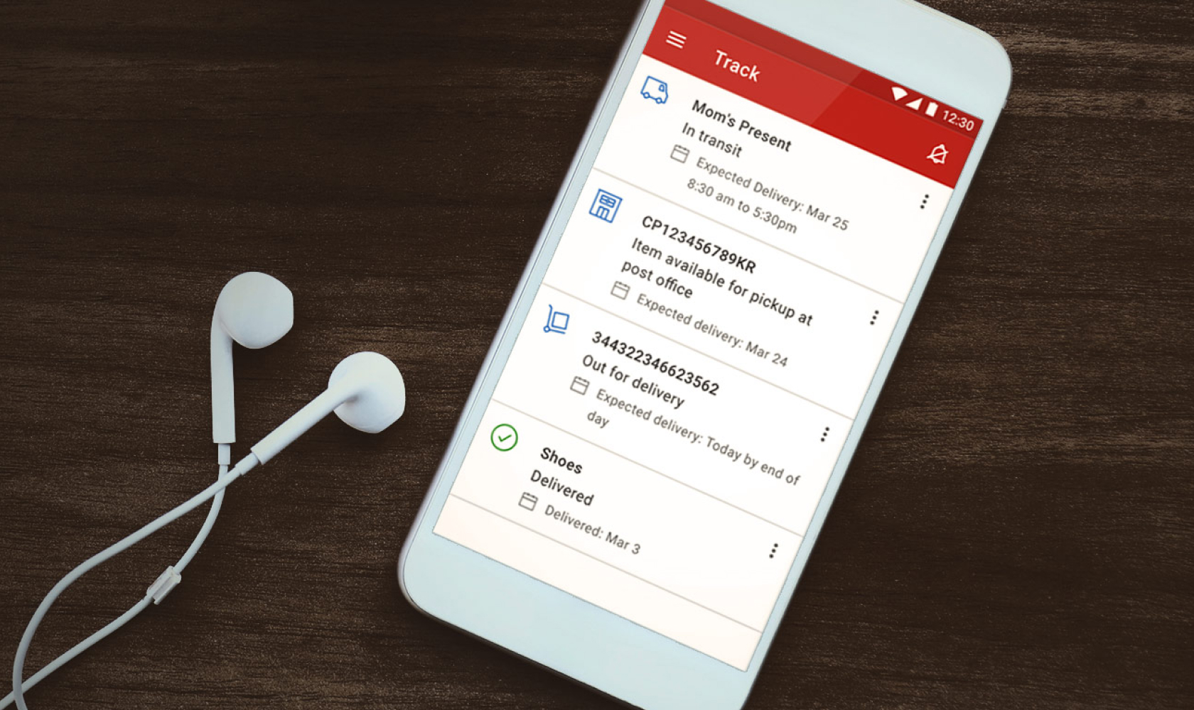 A cellphone is used to track multiple shipments in the Canada Post app. Earbuds rest beside the phone.