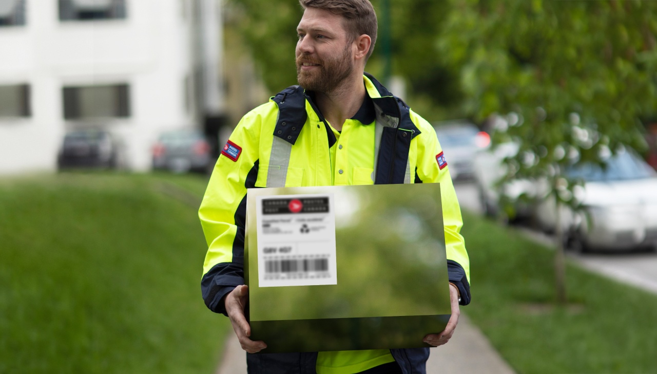 A Canada Post employee carries a carbon- neutral package for delivery.