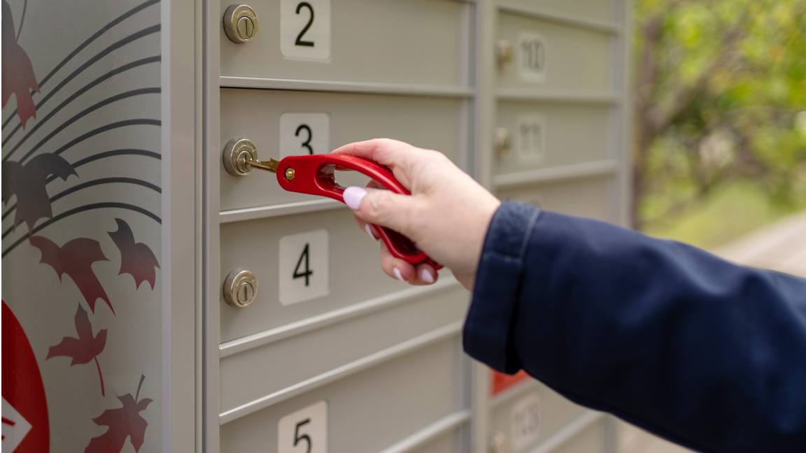 Gros plan sur une main qui déverrouille un compartiment de boîte postale communautaire à l’aide d’un tourne-clé accessible