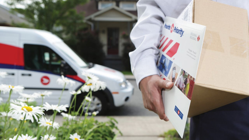 Un employé des postes livre une enveloppe prépayée régionalePriorité de Postes Canada